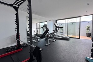 Une salle de sport équipée de matériel d’exercice, de supports pour les poids et d’un tapis de course.