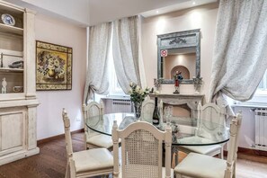 A dining area with a glass table surrounded by chairs, a fireplace with a mirror above it, and a radiator below. - Crispi Little Inn 1 (Roma)