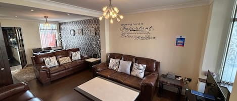 A modern living room with leather sofas, a coffee table, and a wall-mounted quote.