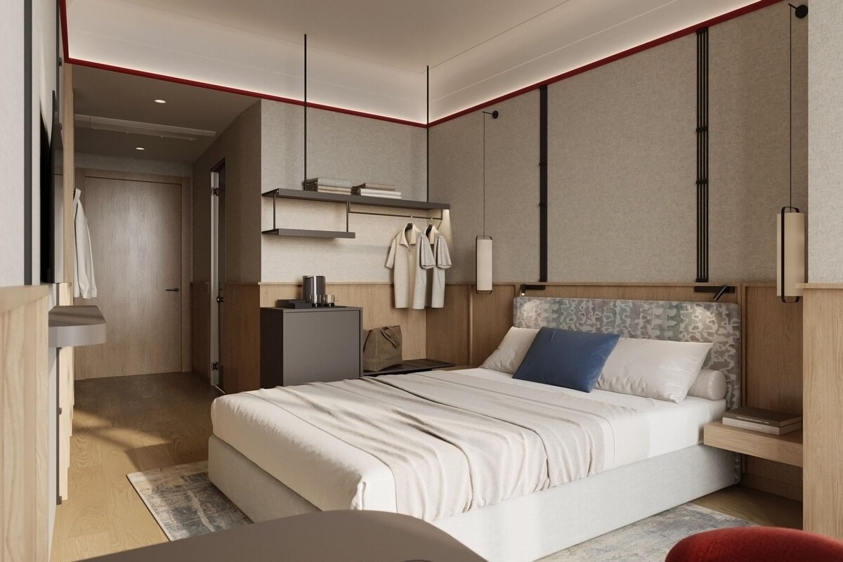 Habitació d'hotel moderna amb llit, taula de nit, armari i escriptori amb cadira.