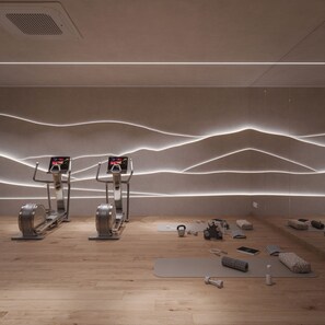 A modern gym with elliptical machines, a yoga mat, kettlebells, and a water bottle on the floor. - Kazzhol Seven Almaty  (Almaty)