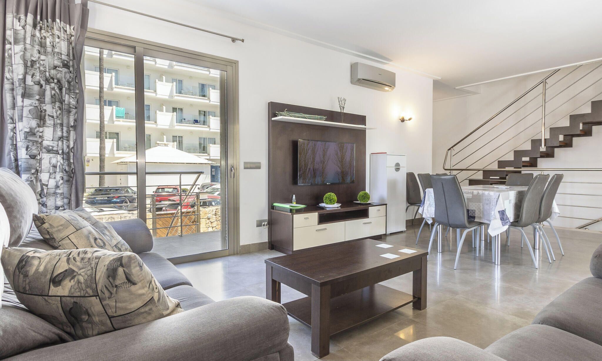 A modern living room with a sofa, coffee table, and a dining area with chairs and a table.