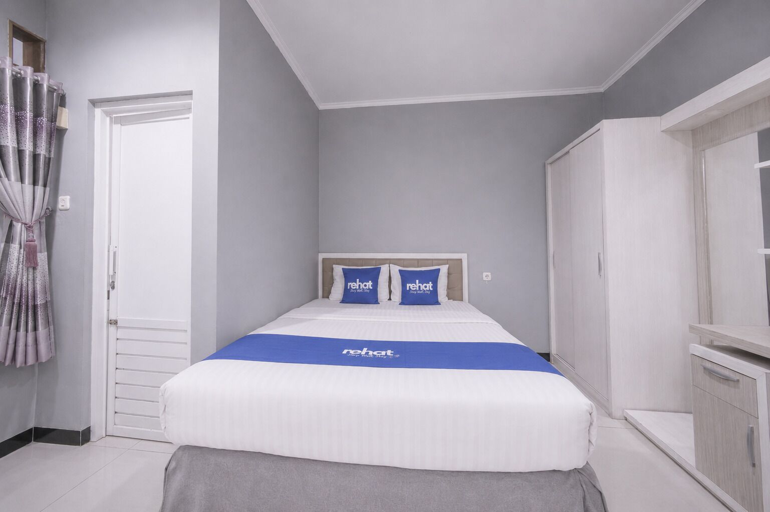 A bedroom with a bed, a wardrobe, and a curtain.
