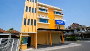 A modern hotel with a yellow facade, multiple floors, and a sign indicating it is a sleep well sleep hotel. - Rehat at The Karins Guest House (Bandung)