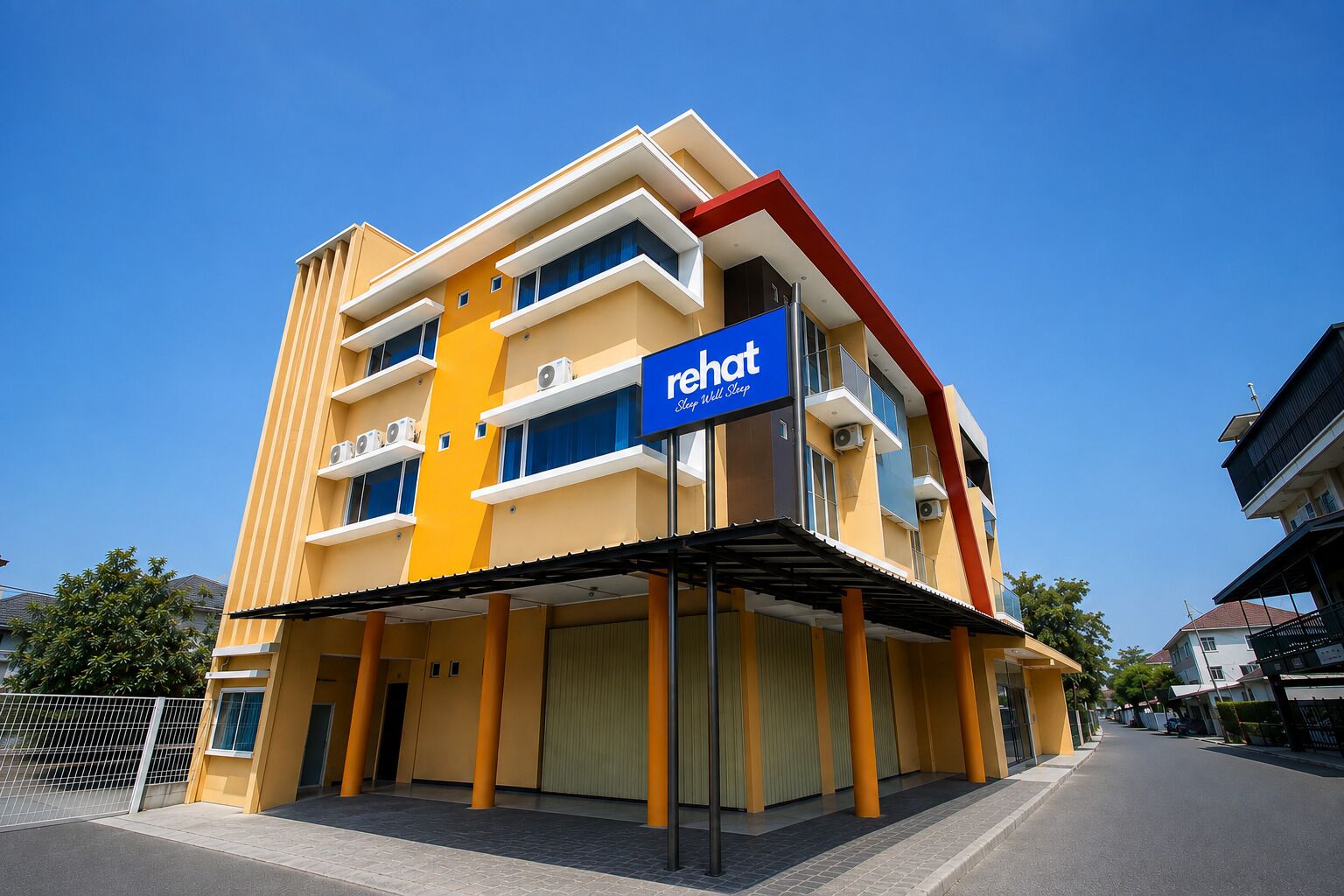 A multi-story hotel with a prominent 'rehat' sign, featuring balconies and air conditioning units.