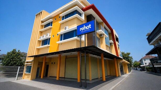 A multi-story hotel with a prominent 'rehat' sign, featuring balconies and air conditioning units. - Rehat at The Karins Guest House (Bandung)