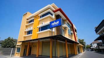 A multi-story hotel with a prominent 'rehat' sign, featuring balconies and air conditioning units.