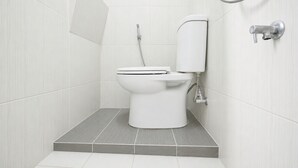 A modern bathroom with a toilet, a shower, and a bidet. - Rehat at The Karins Guest House (Bandung)
