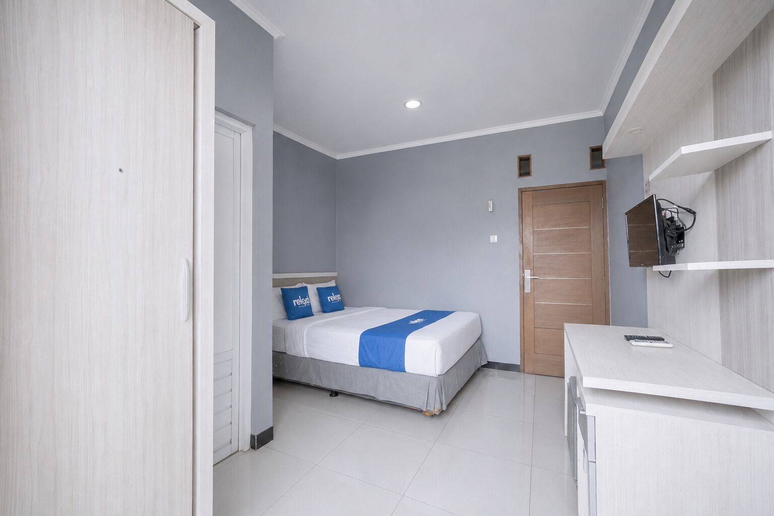 Una habitación de hotel con una cama, un escritorio y un armario.