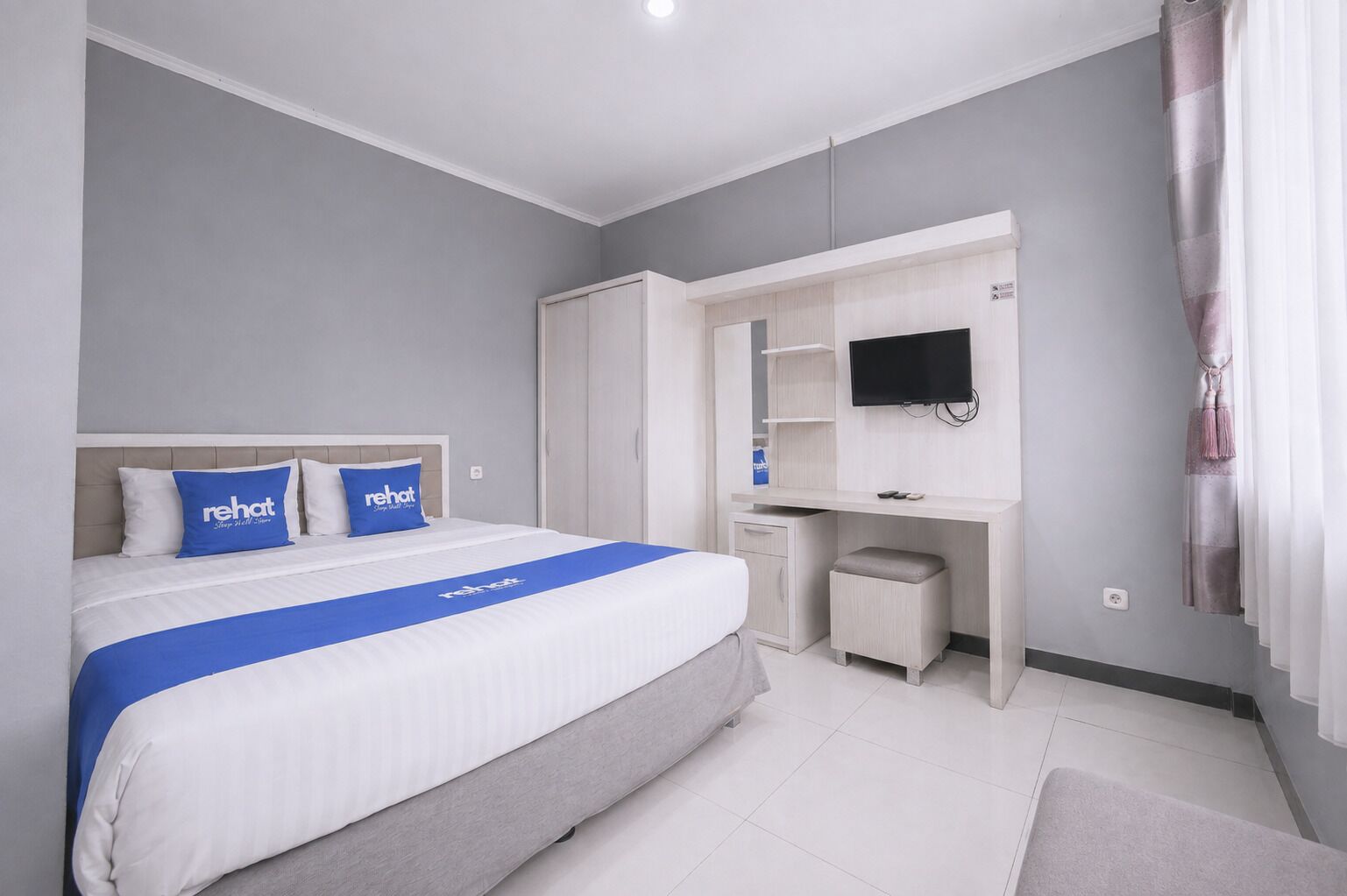 A hotel room with a bed, a desk, a television, and a wardrobe.