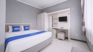 A hotel room with a bed, a desk, a television, and a wardrobe. - Rehat at The Karins Guest House (Bandung)