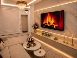 A modern living room with a fireplace, a sofa, a coffee table, and a television mounted on the wall. - Premium Apartment | 5 Min to Airport (Тоshkent)