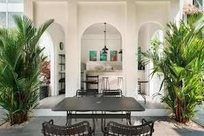 An outdoor dining area with a table and chairs, surrounded by arches and potted plants. - Shanti Rock Residence Koh Phangan  (Koh Phangan)