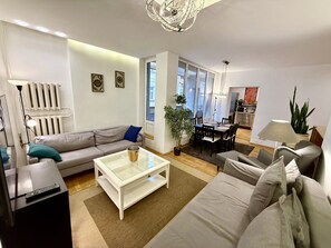 A modern living room with a sofa, coffee table, dining table, and chairs.