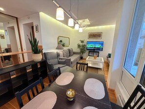 Una sala de estar moderna con comedor, sofá, televisor y un ventanal grande.