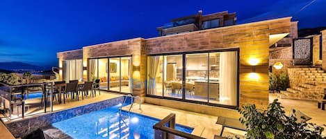 Una casa moderna con piscina, mobiliario exterior y amplias ventanas.