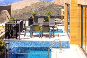 A rooftop pool area with a view of mountains, including a table and chairs, and a small garden. - Luxury Villa Petra w ndoor Heated Pool, Sauna (Kas)