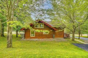 Eine Holzhütte mit geneigtem Dach, einer Veranda und einer kleinen angebauten Garage.