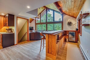A modern kitchen with a wooden island, large windows, and a view of the outdoors. - Mountain View & Hot Tub in Ellicottville New York (Ellicottville)