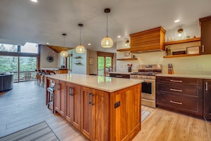 A modern kitchen with wooden cabinets, a large island, and pendant lighting. - Mountain View & Hot Tub in Ellicottville New York (Ellicottville)
