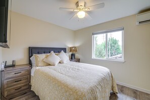 Ein Schlafzimmer mit Bett, Nachttisch, Lampe, Deckenventilator und Fenster.