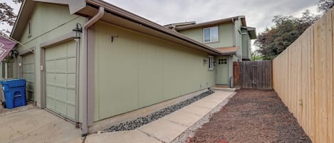 A two-story house with a garage, a wooden fence, and a gravel driveway.