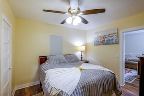 A bedroom with a bed, a ceiling fan, a painting, and a door. - Couple’s Casita Near Historic Downtown Roswell! (Roswell)