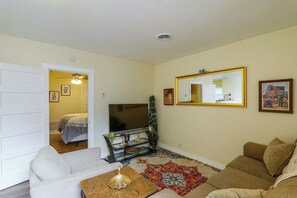 A living room with a sofa, a coffee table, a television, and a decorative mirror. - Couple’s Casita Near Historic Downtown Roswell! (Roswell)