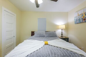 Une chambre à coucher avec un lit, une lampe de chevet, une porte et une fenêtre avec des stores.