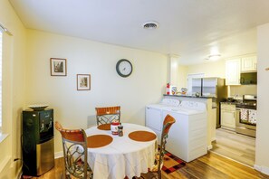 A compact kitchen with a washing machine, a dining table with chairs, and a clock on the wall. - Couple’s Casita Near Historic Downtown Roswell! (Roswell)