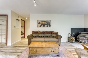 Ein Wohnzimmer mit einer Couch, einer Holzkiste und Wandkunst mit Bärenmotiven.