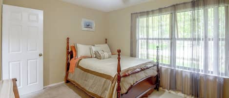 Une chambre à coucher avec un lit à baldaquin, un ventilateur de plafond, une fenêtre avec des rideaux légers et une porte.