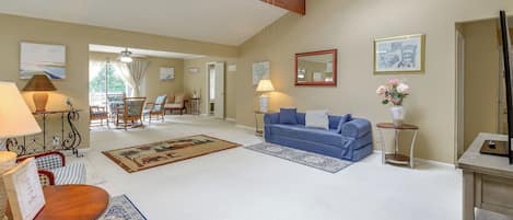 Una sala de estar amplia con un sofá azul, una mesa de centro de madera y una zona de comedor con sillas y una mesa.