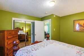 A bedroom with a bed, dresser, and a door leading to another room. - Walk to Downtown Roswell! Quaint Home w/ Patios (Roswell)