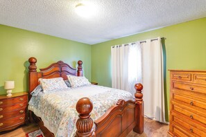 A bedroom with a wooden bed, a nightstand, a dresser, and a window with curtains. - Walk to Downtown Roswell! Quaint Home w/ Patios (Roswell)