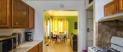 Une cuisine dotée de meubles en bois, d’une cuisinière, d’un four à micro-ondes et d’un coin repas avec une table et des chaises.