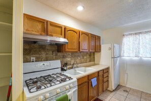 A kitchen with wooden cabinets, a white stove, a sink, and a refrigerator.