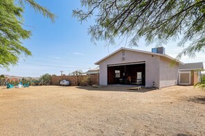A single-story building with a garage, a fenced yard, and outdoor seating. - Heated Pool, Spa & Game Room: Yucca Valley Retreat (Yucca Valley)