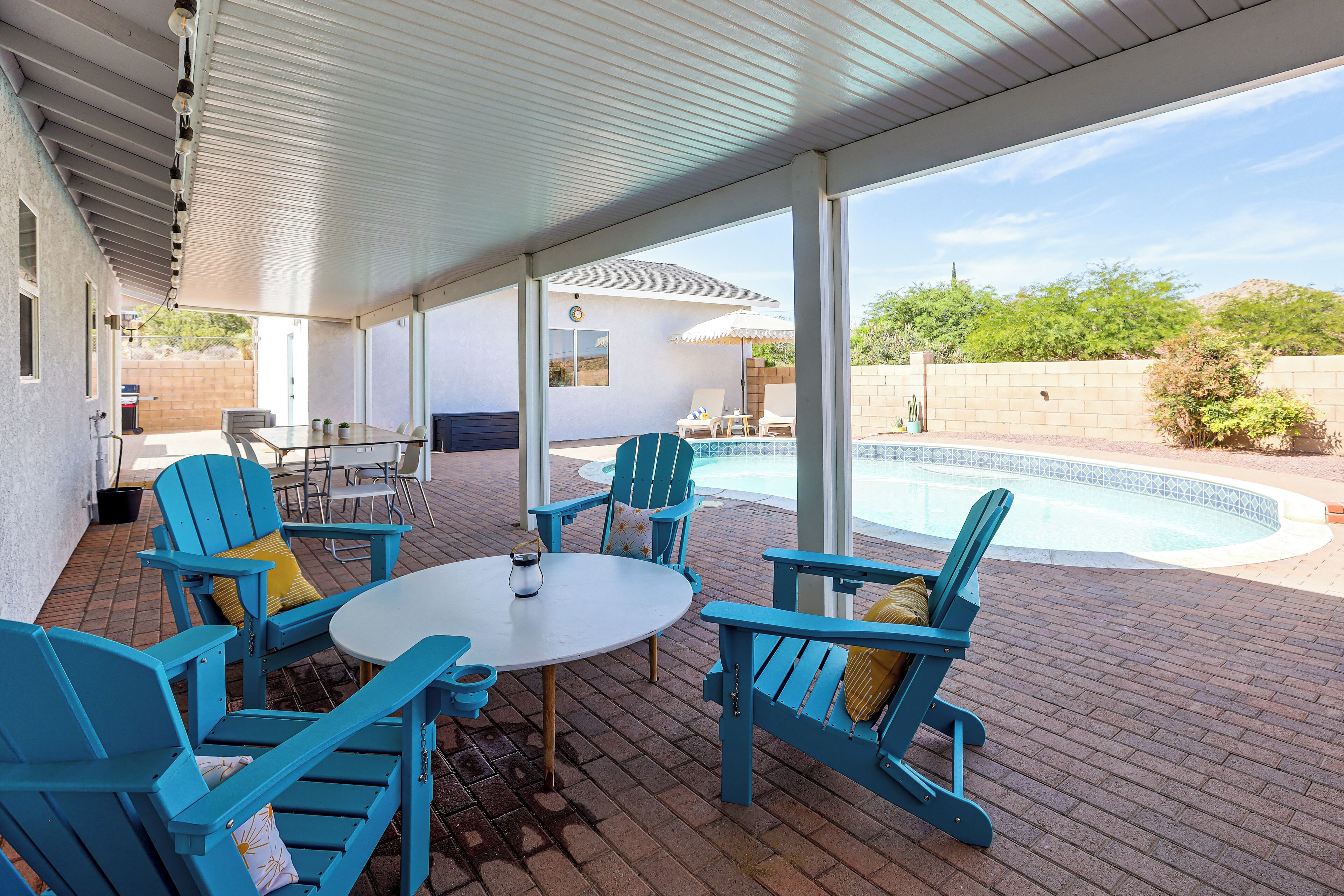 A covered patio area with a pool, outdoor furniture, and a view of the surrounding landscape.