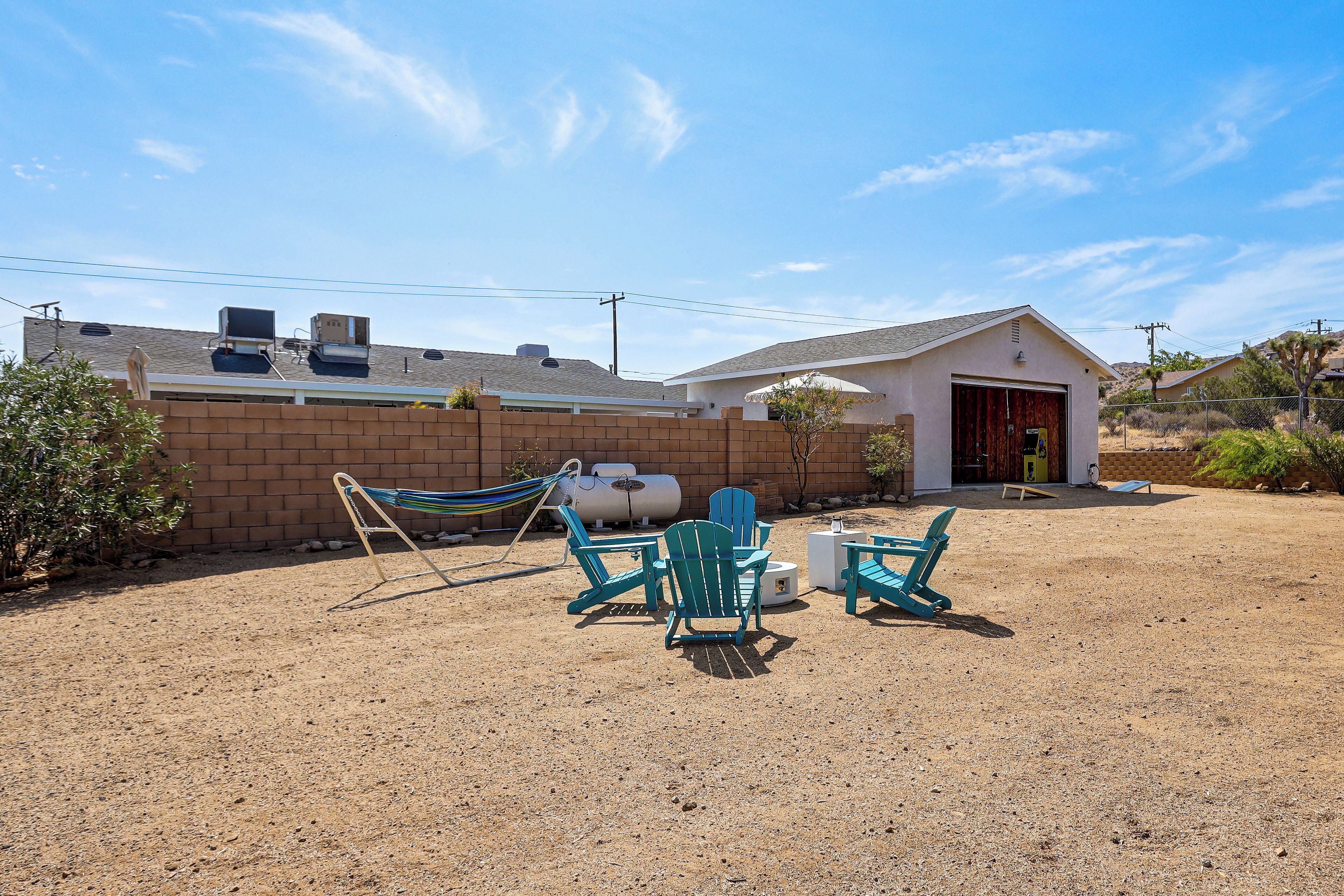 A fenced backyard with a patio area, outdoor seating, and a building with a garage.