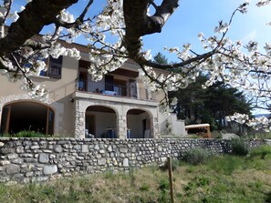 A stone-walled building with arched openings, a balcony, and a stone staircase leading to an upper level.