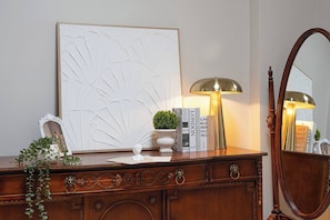 Un aparador de madera con espejo, una obra de arte enmarcada, una lámpara y objetos decorativos.