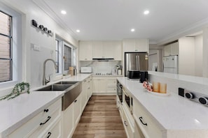 Una cocina moderna con armarios blancos, electrodomésticos de acero inoxidable y suelo de madera.