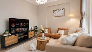 Ein modernes Wohnzimmer mit Flachbildfernseher, einer Couch, einem Couchtisch und einer Zimmerpflanze.