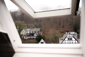 Vista de una zona residencial con casas, incluyendo una casa con tejado a dos aguas y otra con fachada blanca y detalles oscuros.