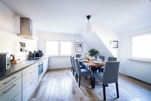 Una cocina moderna con comedor, piso de madera y vista al exterior.