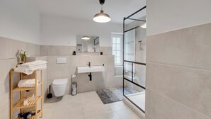 Un baño moderno con inodoro, lavamanos y zona de ducha.