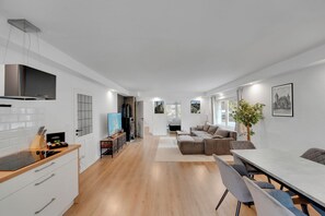 Una cocina moderna con horno integrado, un comedor con mesa y sillas, y una sala de estar con sofá.