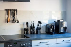 A modern kitchen with a stove, coffee maker, and various utensils.