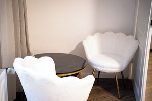 Une pièce d’angle avec une table ronde et deux chaises blanches au design original, caractérisé par un motif à festons.